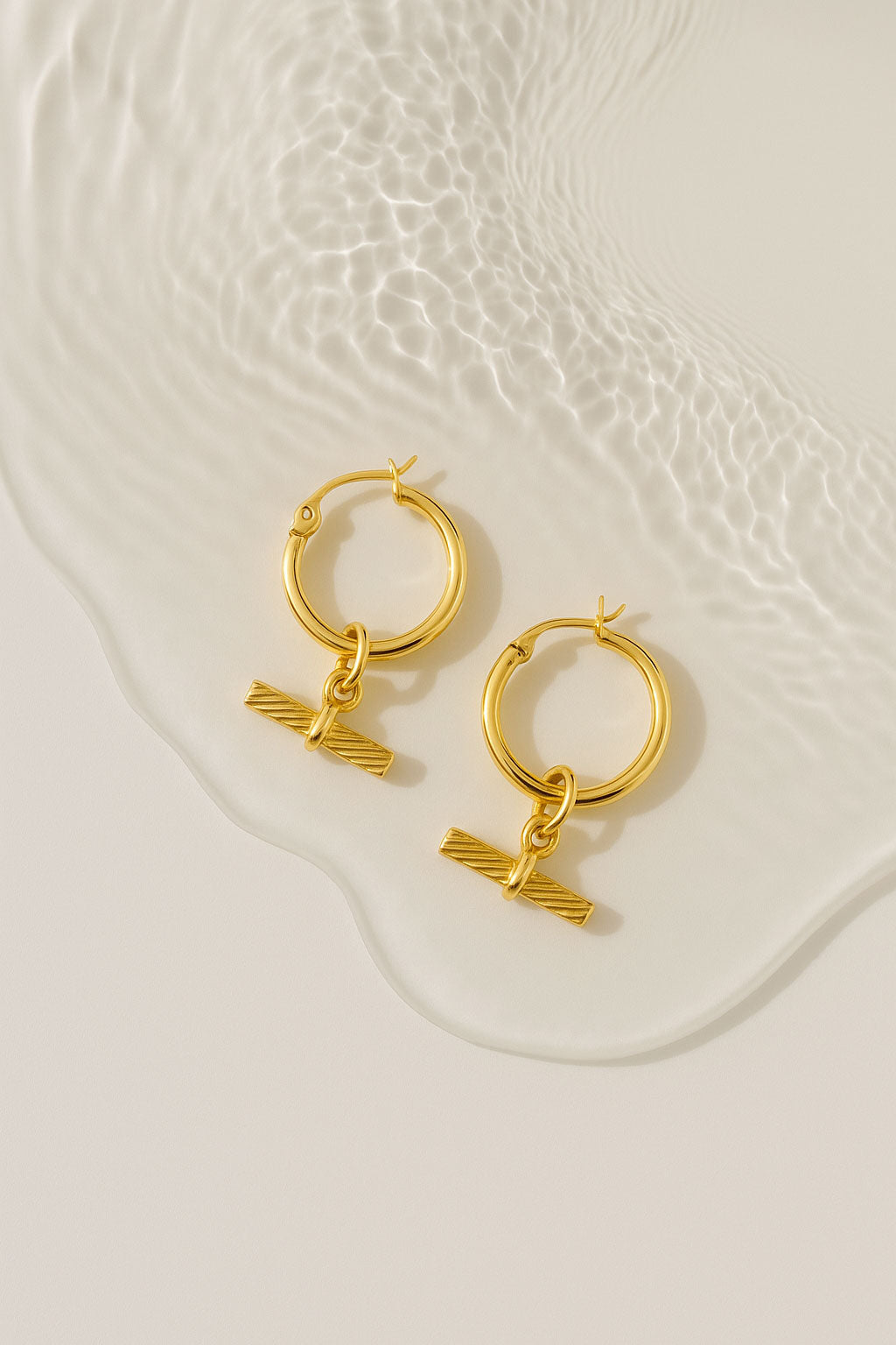 Gold hoop earrings with T-bar charms.